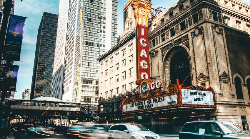 A historic Chicago theatre surrounded by passing cars