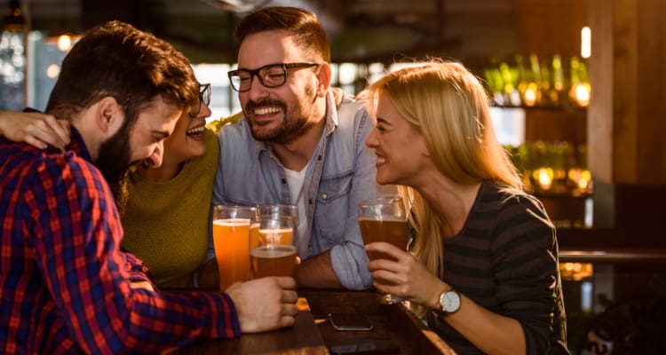 friends smile and hold their beer glasses at a brewery