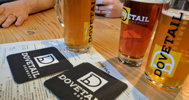 drink glasses filled with beer and two coasters with "dovetail brewery" logo on them