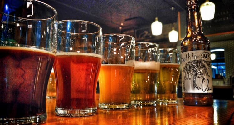 a row of glasses with different colored beers in them