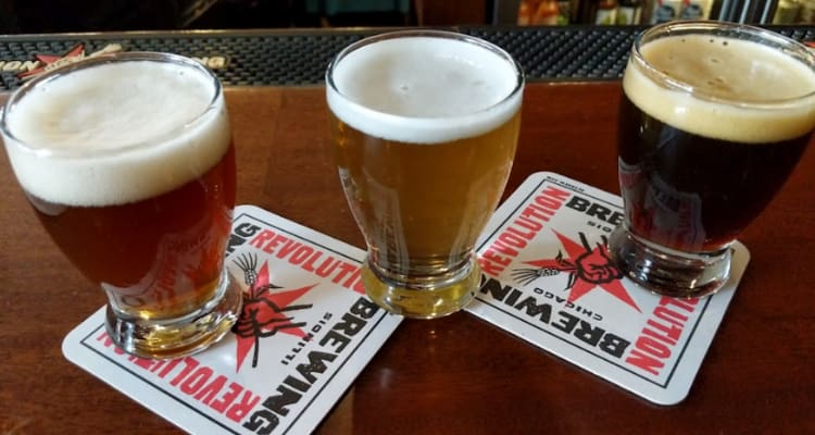 three foamy beer glasses with branded coasters under them