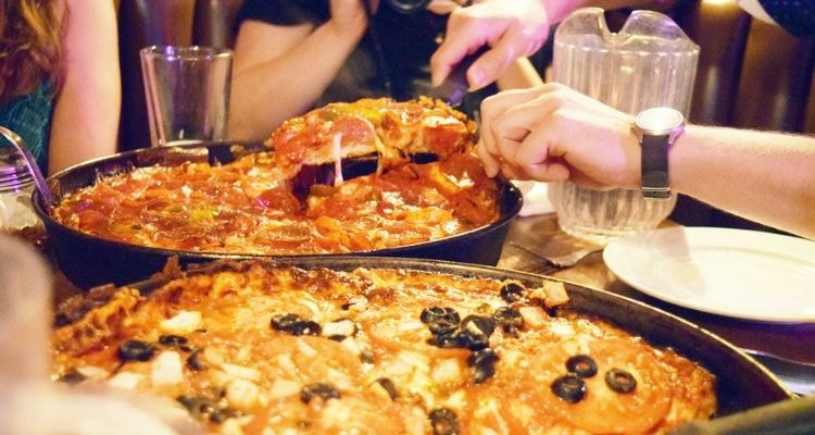 People cutting a slice of Chicago deep dish pizza