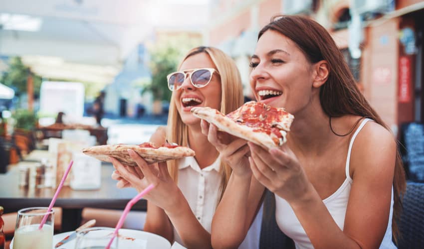 Friends smiling and eating pizza