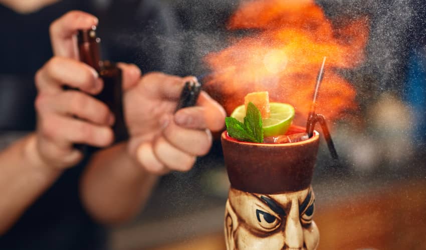 a bartender making a flaming cocktail at a bar