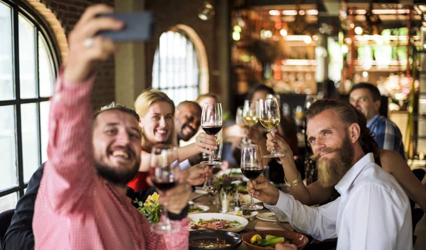 A group of friends toasting and taking a selfie at a restaurant 